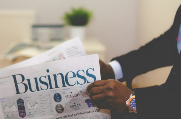 Person holding a newspaper with the headline "Business."